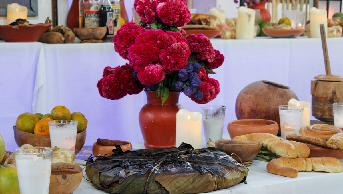 Altar de Hanal Pixán con elementos como el mucbipollo, jícaras, velas y flores.