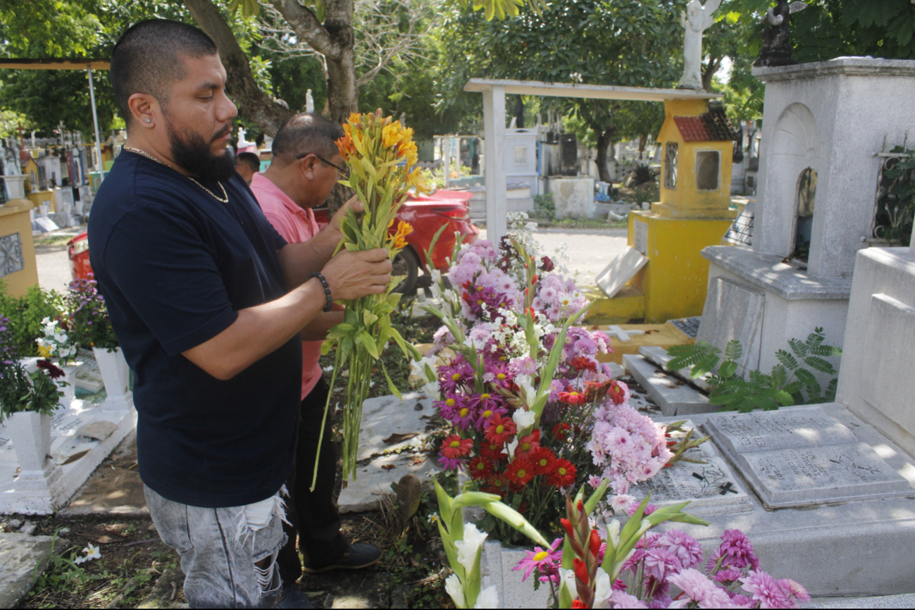 Familiares llevan flores a las tumbas de sus difuntos