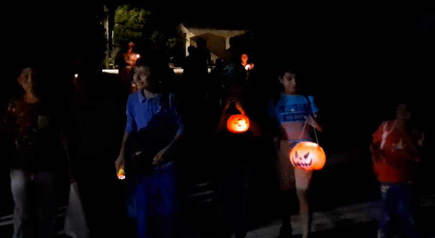 Los niños caminan en grupos con calabazas, velas y veladoras para iluminar sus caminos