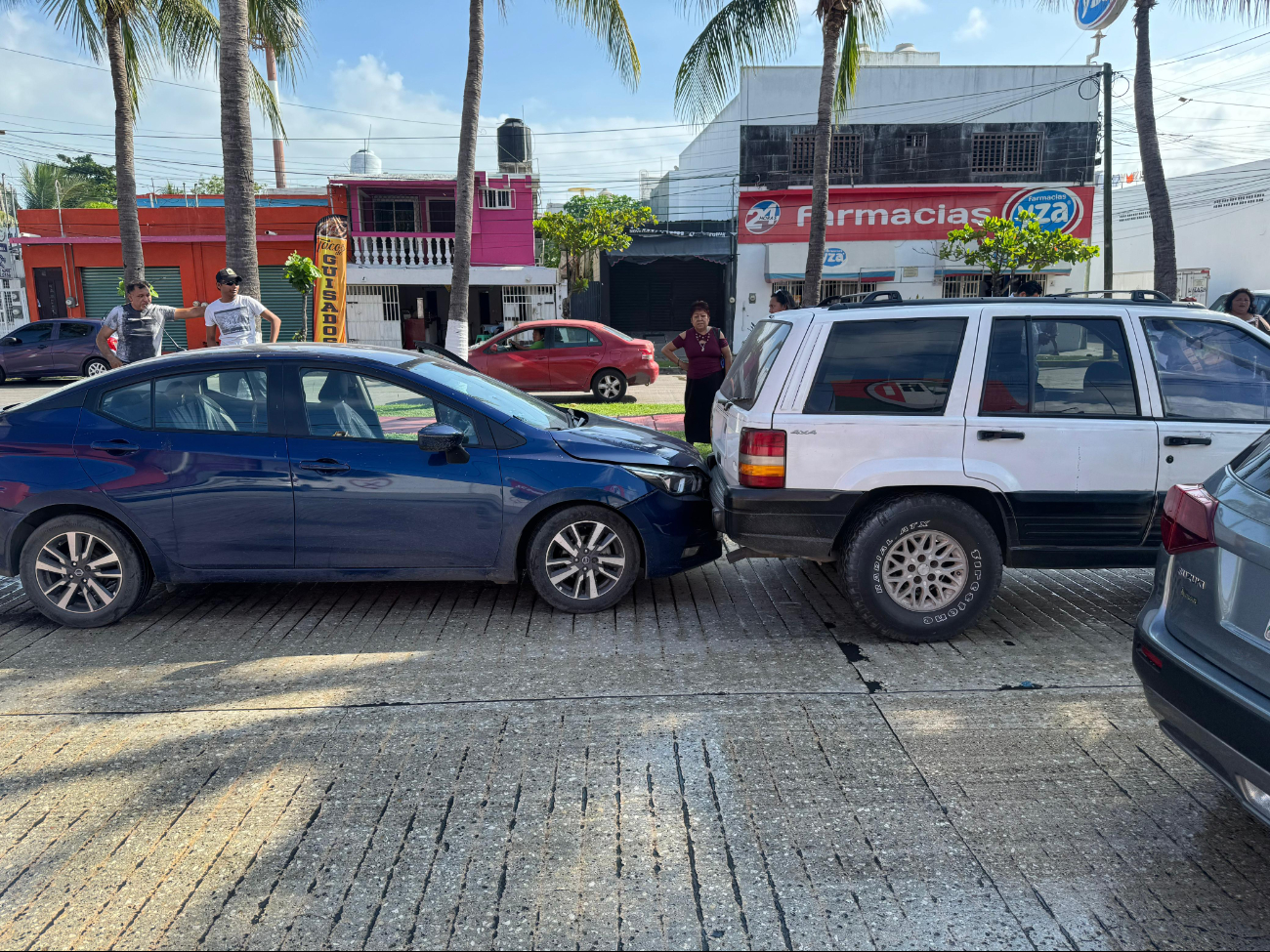 El Nissan azul fue chocado por una camioneta de redilas Nissan blanca debido al pavimento mojado y falta de precaución