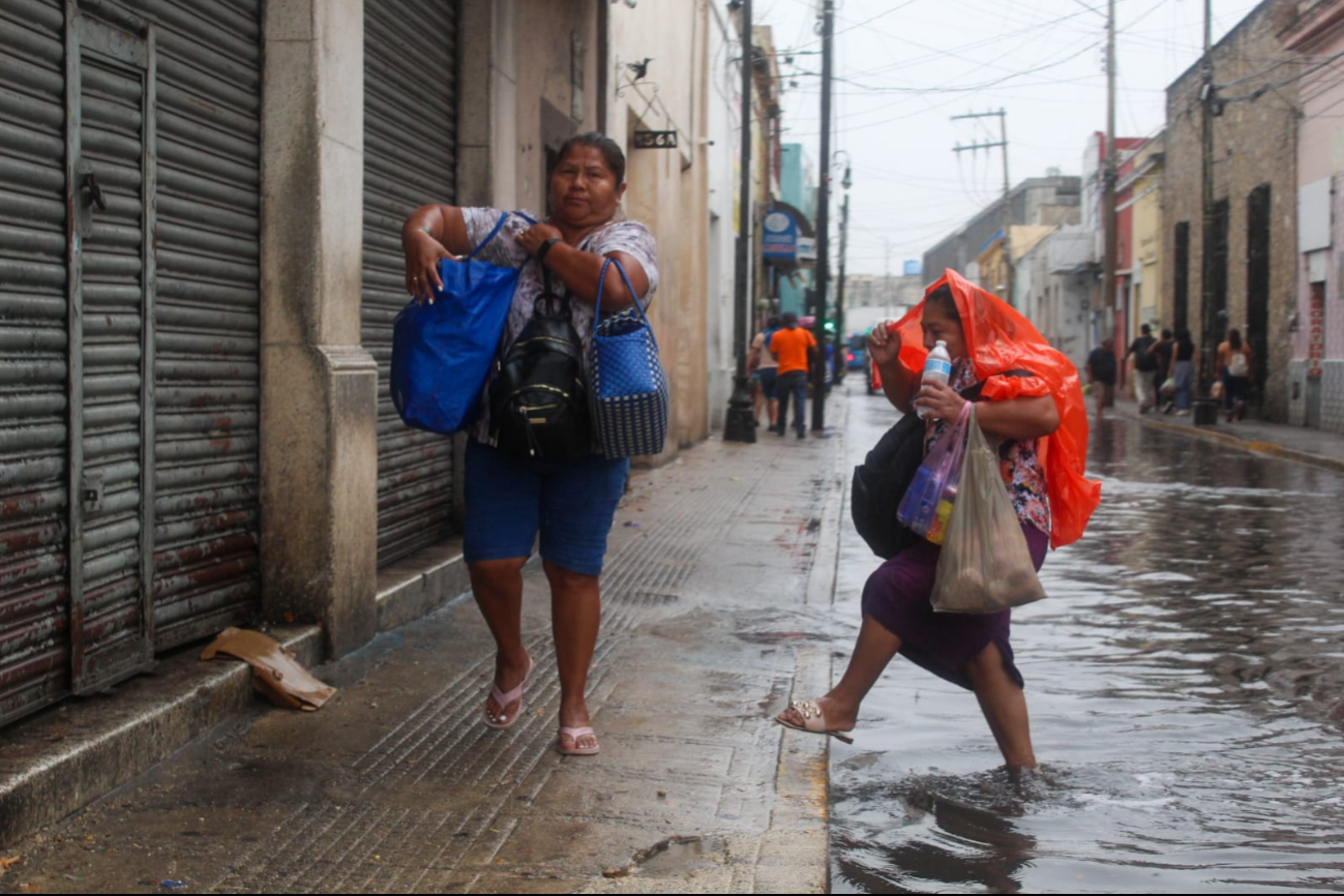 Mujer cruza la calle, a pesar de la inundación en Mérida