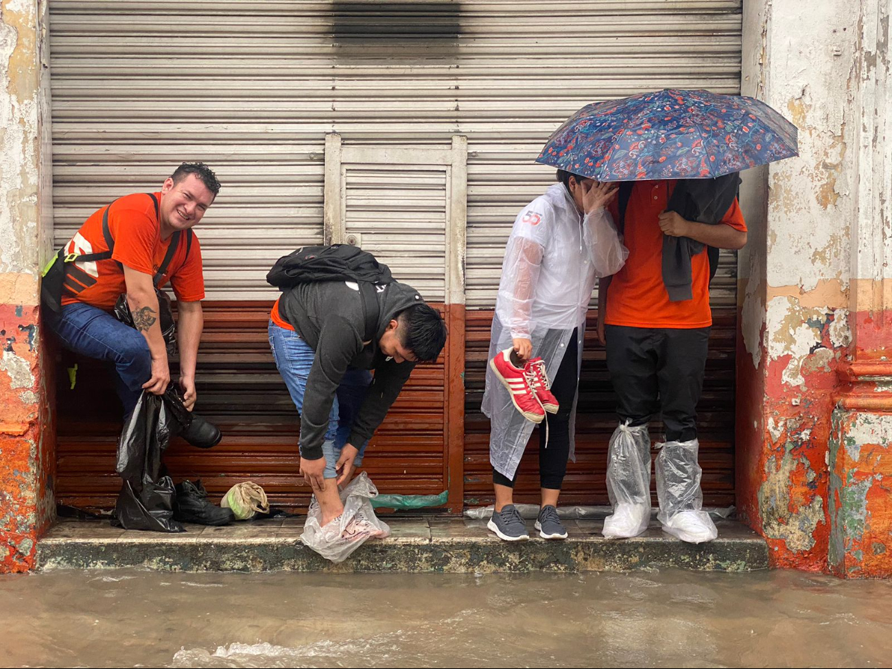 Trabajadores protegen su calzado, a causa de las inundaciones, en Mérida