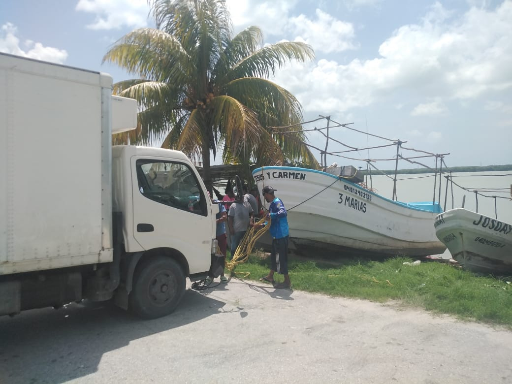 Pescadores elevan lanchas a la orilla para evitar daños por lluvia y olas.