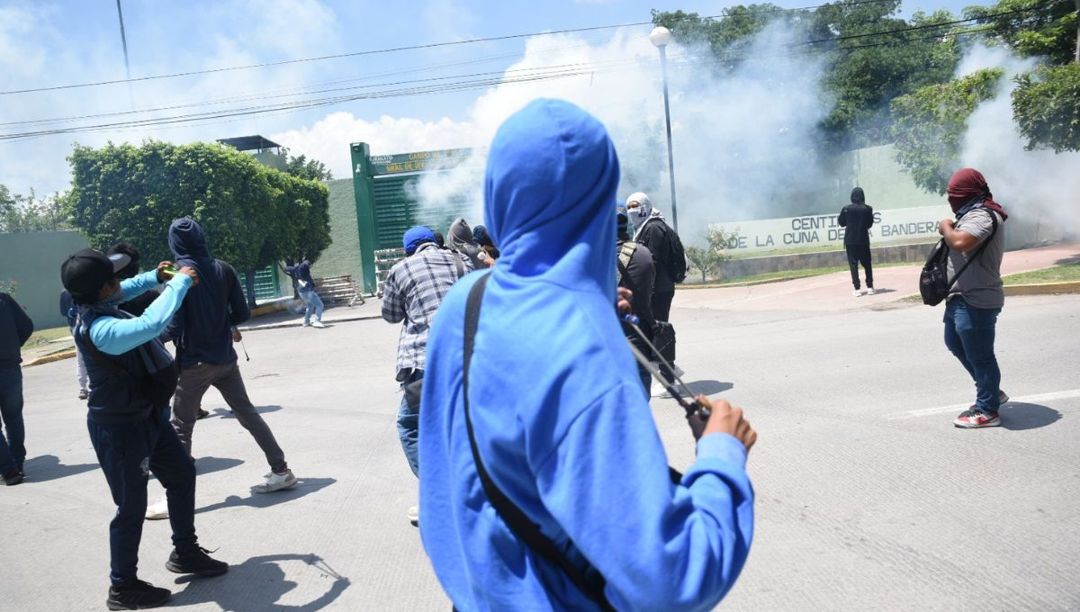 Normalistas de Ayotzinapa lanzan petardos y queman autos en protesta en cuartel militar de Iguala