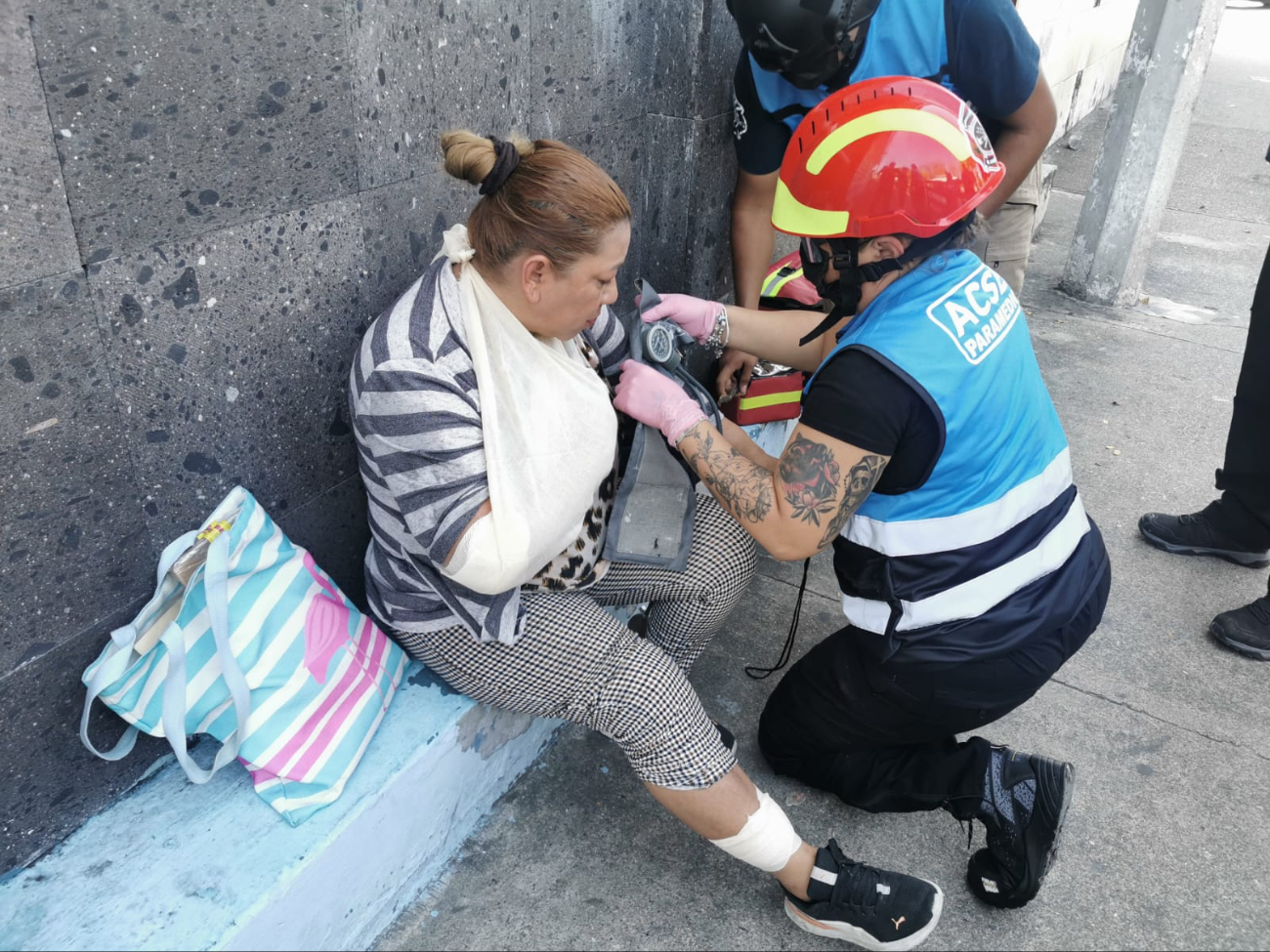 Paramédicos atienden a la mujer herida con vendajes en brazo y pierna