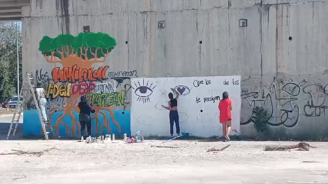 Un grupo de manifestantes realiza pintas bajo un puente en Playa del Carmen