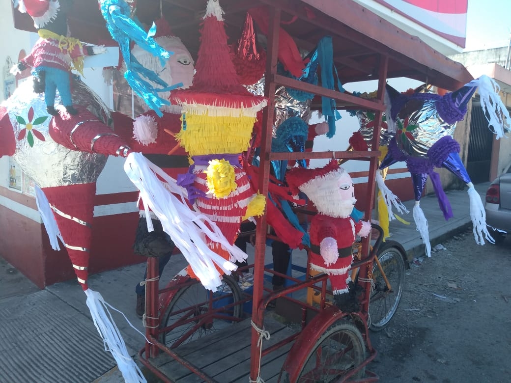 Don Isidro lleva en su triciclo piñatas de todo tipo, desde estrellas hasta a Santa Claus