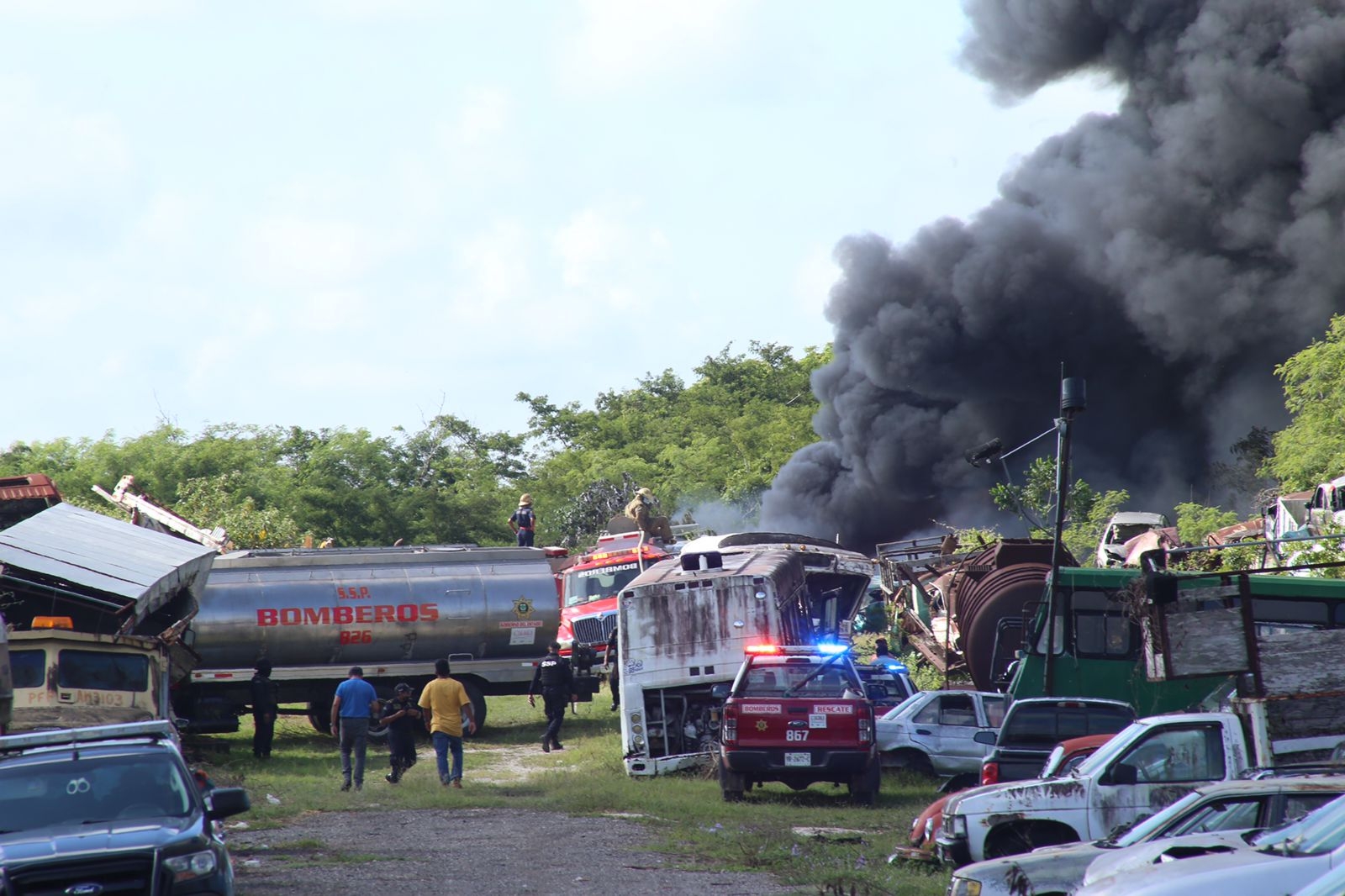 Bomberos tratan de sofocar el incendio en un depósito de carros chatarra