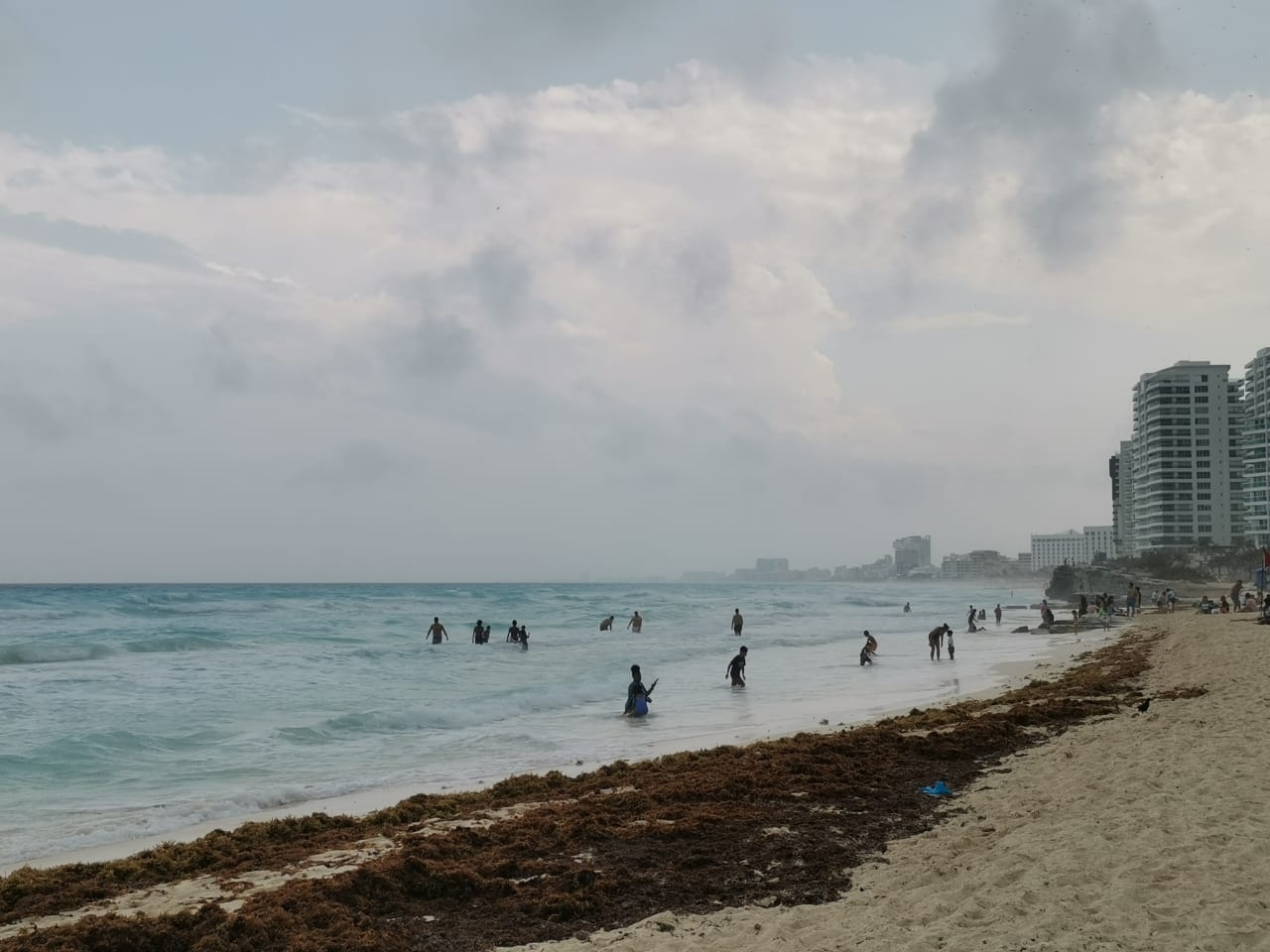 Bañistas acuden a playas de Cancún a pesar de la lluvia y el sargazo: FOTOS